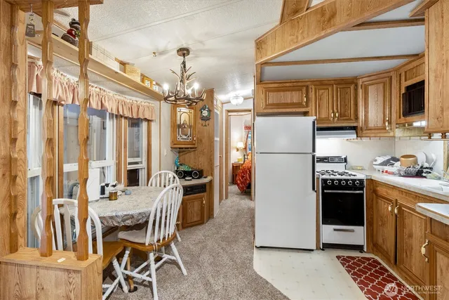 a kitchen with stainless steel appliances granite countertop a refrigerator a stove a sink dishwasher and a dining table with wooden floor