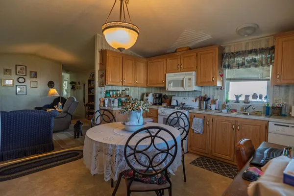 a kitchen with granite countertop a table chairs stove top oven and sink