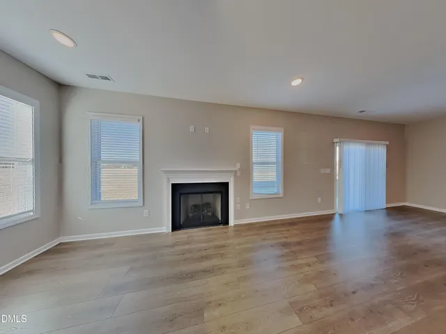 an empty room with windows and fireplace