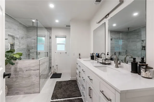 a bathroom with a double vanity sink a toilet and shower