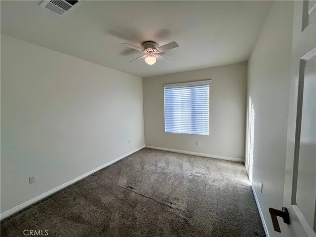 en empty room with windows and ceiling fan