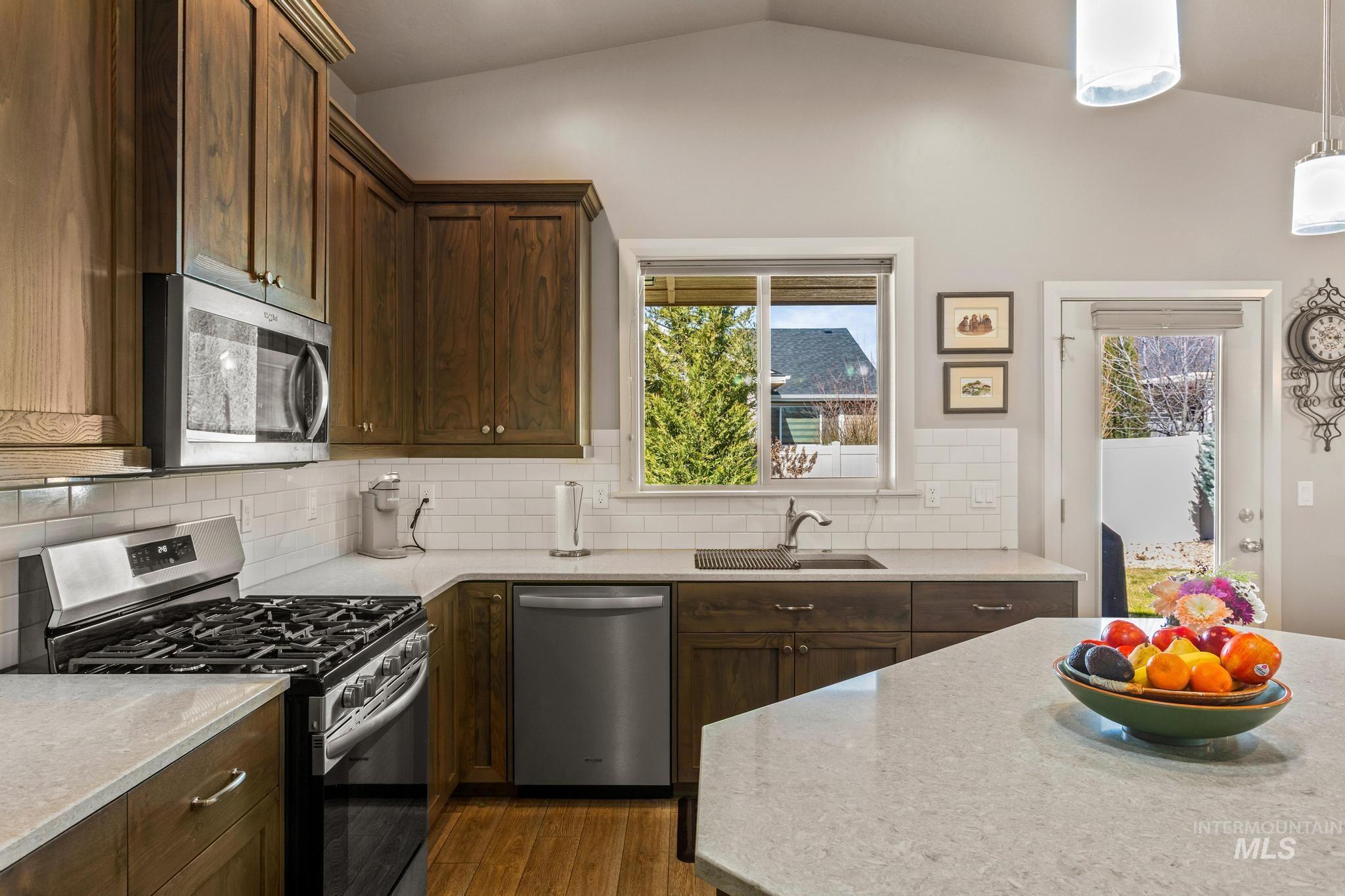 5832 West Rotherham Drive Eagle, ID 83616 - Photo 15 of 42 Kitchen with stainless steel appliances, dark wood-style flooring, light stone countertops, and healthy amount of natural light