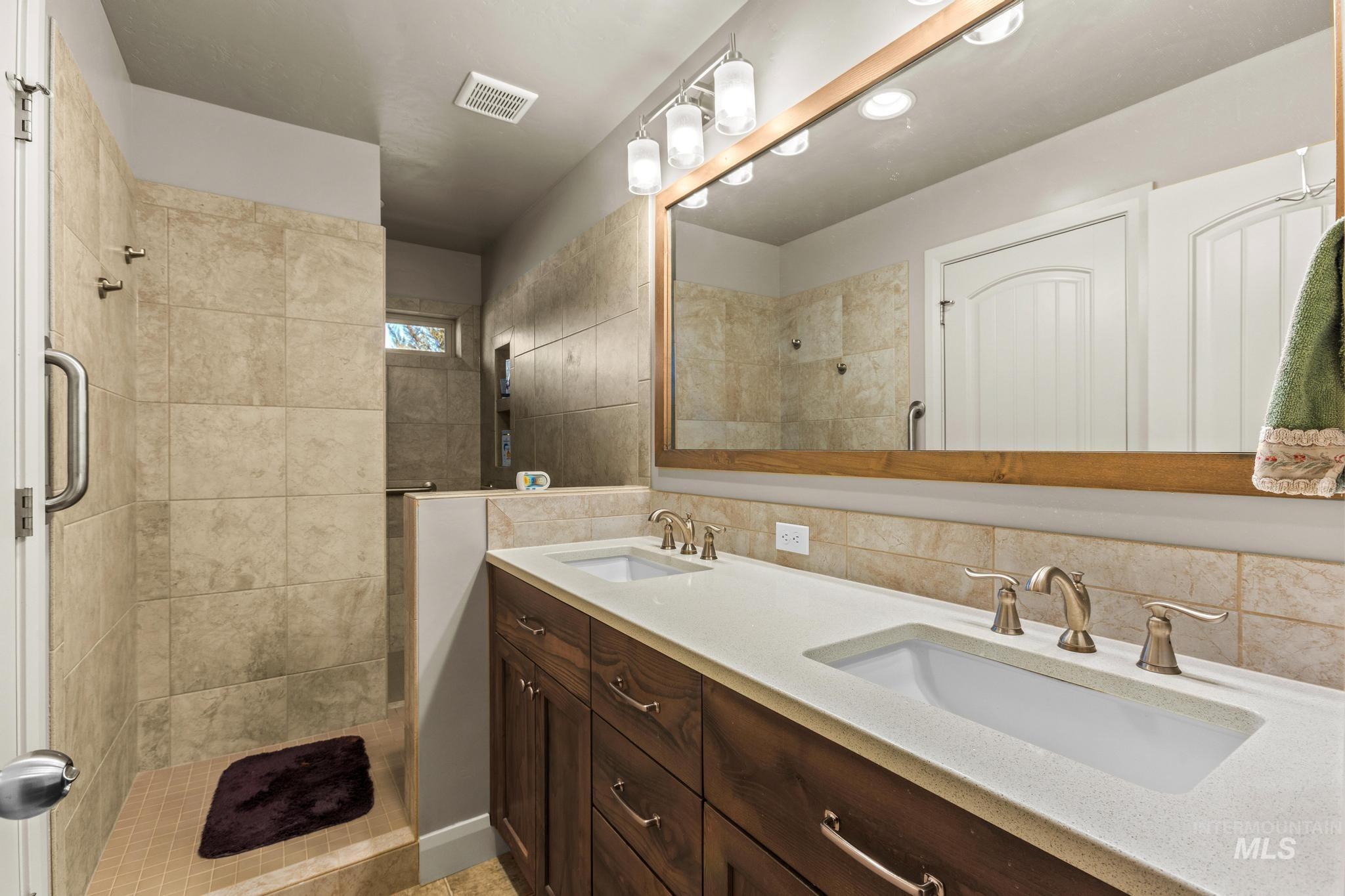 5832 West Rotherham Drive Eagle, ID 83616 - Photo 22 of 42 Bathroom with double vanity, backsplash, and a stall shower