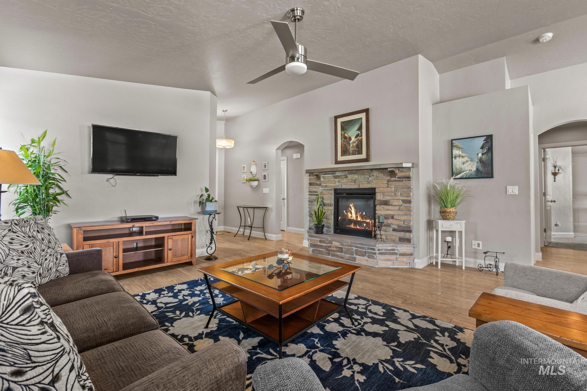 5832 West Rotherham Drive Eagle, ID 83616 - Photo 6 of 42 Living area featuring arched walkways, wood finished floors, ceiling fan, a textured ceiling, and a fireplace