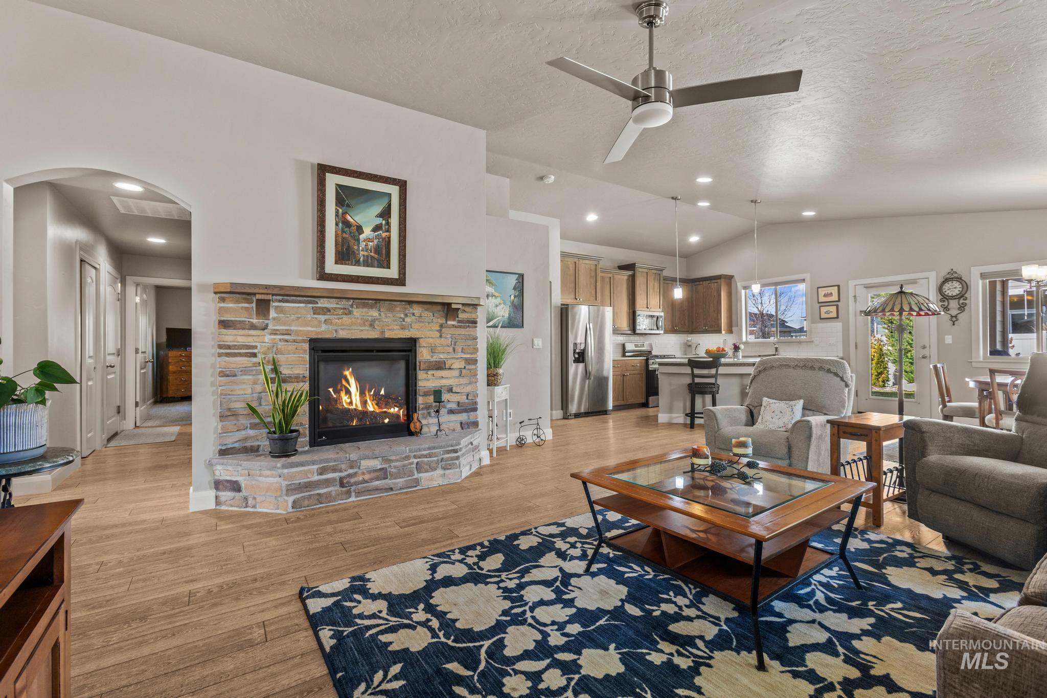 5832 West Rotherham Drive Eagle, ID 83616 - Photo 7 of 42 Living room with a ceiling fan, light wood-style flooring, a fireplace, and arched walkways