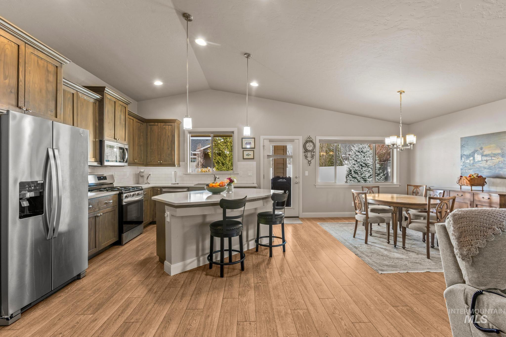 5832 West Rotherham Drive Eagle, ID 83616 - Photo 9 of 42 Kitchen featuring stainless steel appliances, suspended lighting, a breakfast bar area, a kitchen island, and backsplash