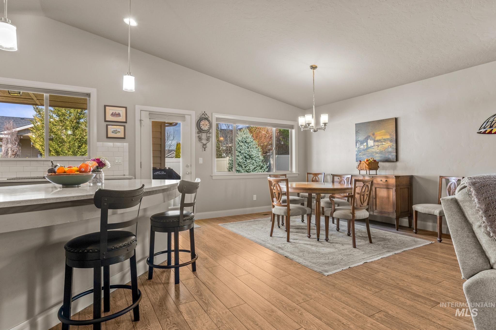 5832 West Rotherham Drive Eagle, ID 83616 - Photo 10 of 42 Dining area featuring lofted ceiling, light wood-type flooring, a chandelier, and plenty of natural light