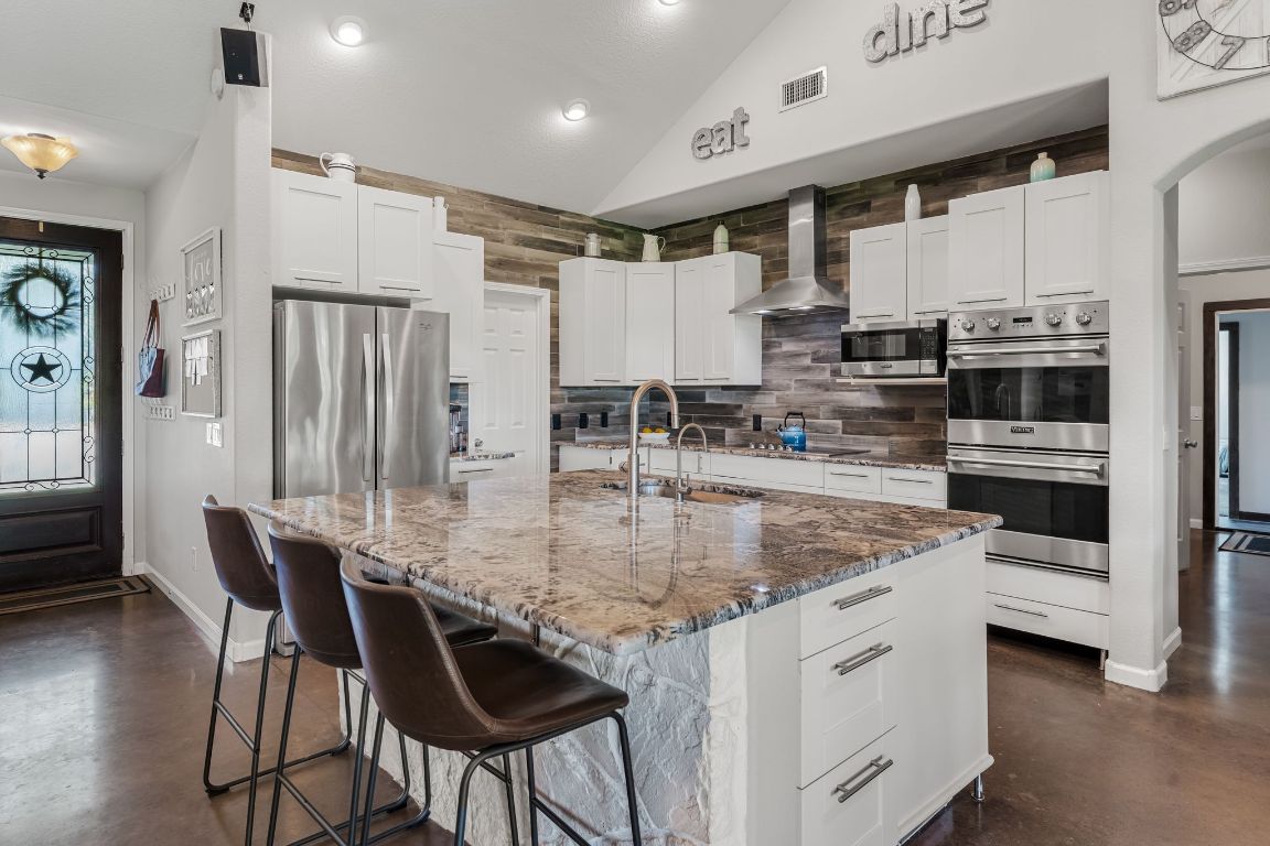 4204 Arthur Circle Leander, TX 78641 - Photo 15 of 40 a kitchen with stainless steel appliances granite countertop a kitchen island a stove a table and chairs
