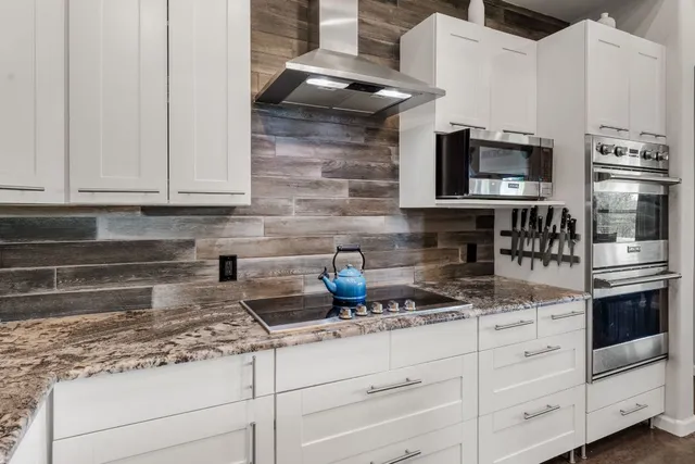 a kitchen with stainless steel appliances granite countertop a stove and white cabinets