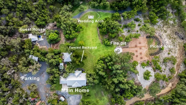 an aerial view of residential house with outdoor space and trees all around