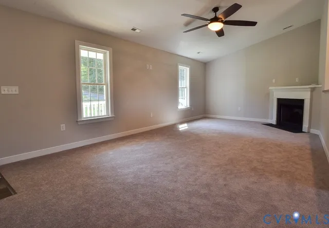 an empty room with windows and fireplace