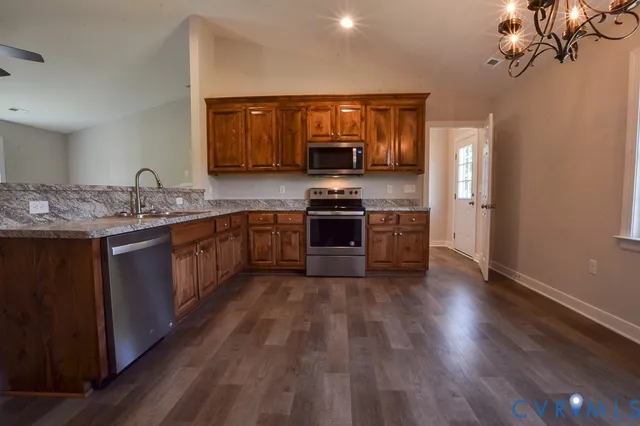 a kitchen with stainless steel appliances granite countertop wooden cabinets a stove top oven a sink and dishwasher