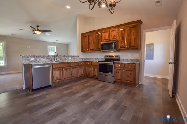a kitchen with stainless steel appliances granite countertop a sink cabinets and wooden floor