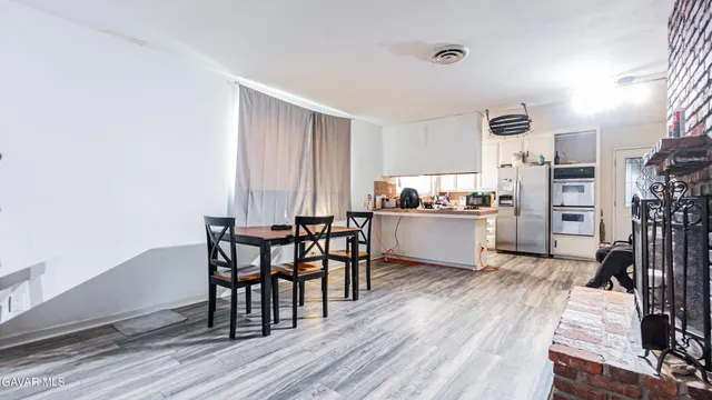 a kitchen with stainless steel appliances a dining table chairs and a refrigerator