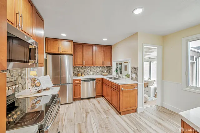 a kitchen with stainless steel appliances granite countertop a stove refrigerator sink and dishwasher with wooden floor