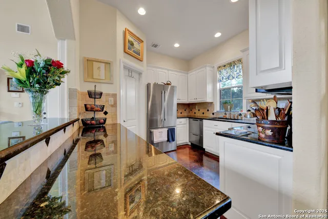 a kitchen with granite countertop white cabinets and white appliances