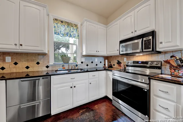 a kitchen with granite countertop a sink stove and microwave