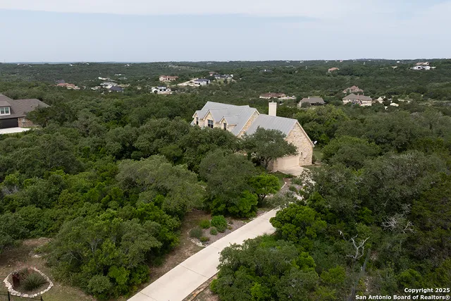 an aerial view of residential house with outdoor space and trees all around