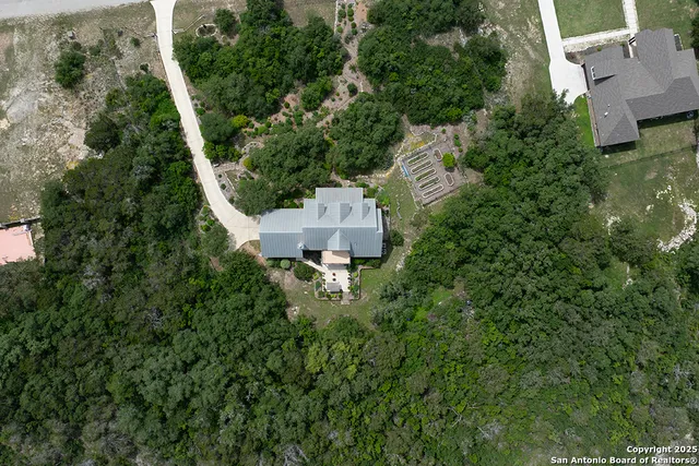 an aerial view of a house with pool outdoor space and trees all around