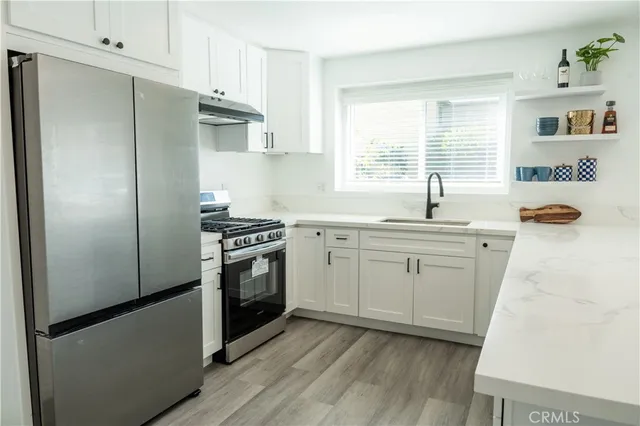 a kitchen with stainless steel appliances a refrigerator sink and wooden floor