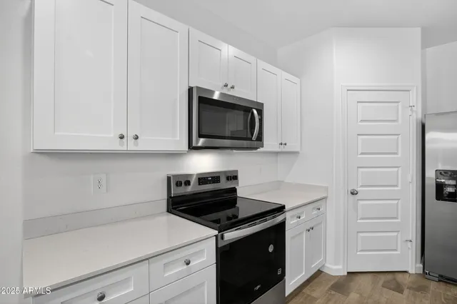 a kitchen with white cabinets and black appliances