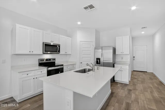 a kitchen with a sink a stove a refrigerator and white cabinets