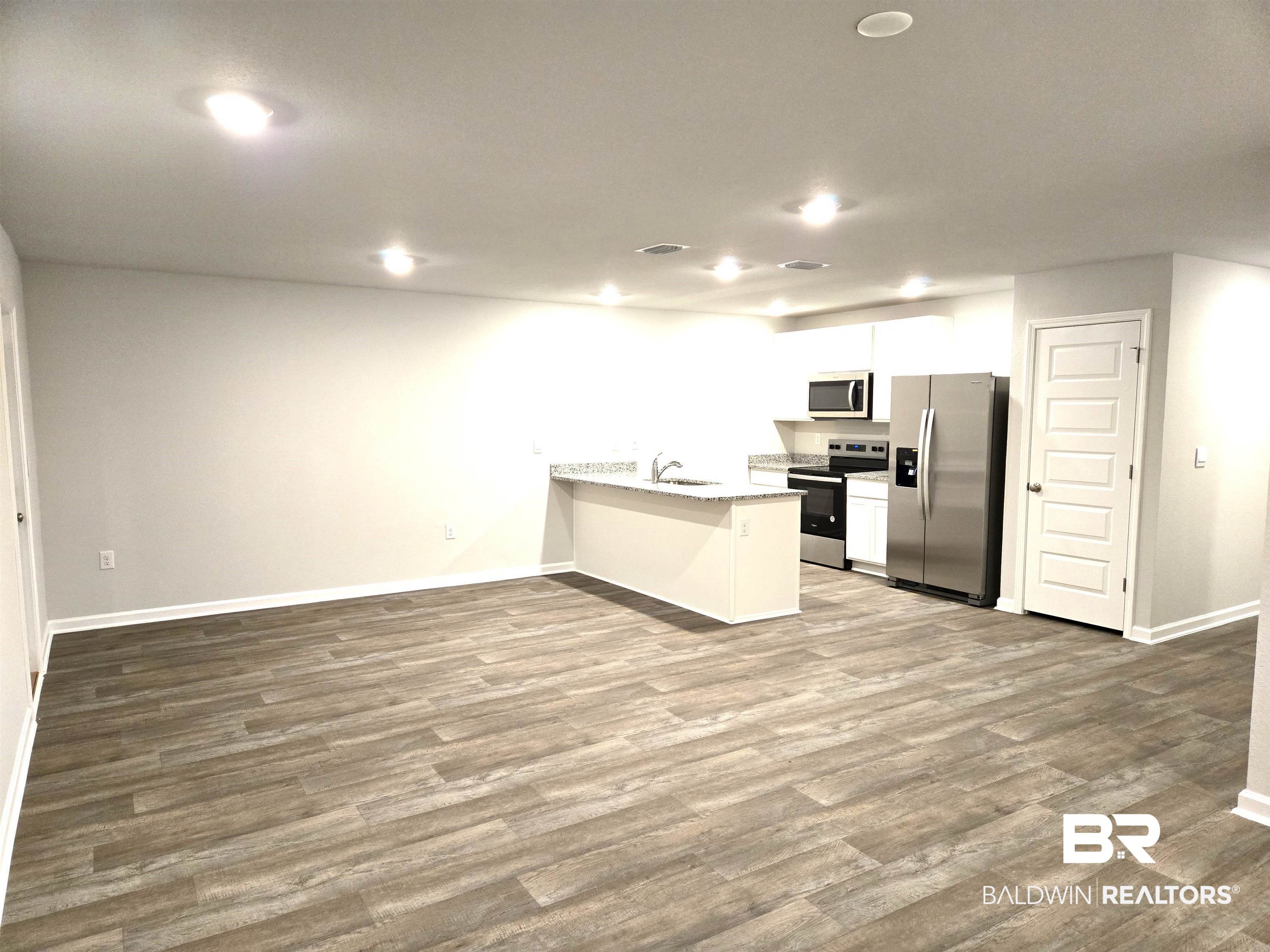 24227 Veranda Circle Elberta, AL 36530 - Photo 6 of 36 Kitchen with appliances with stainless steel finishes, hardwood / wood-style flooring, a kitchen breakfast bar, white cabinets, and kitchen peninsula