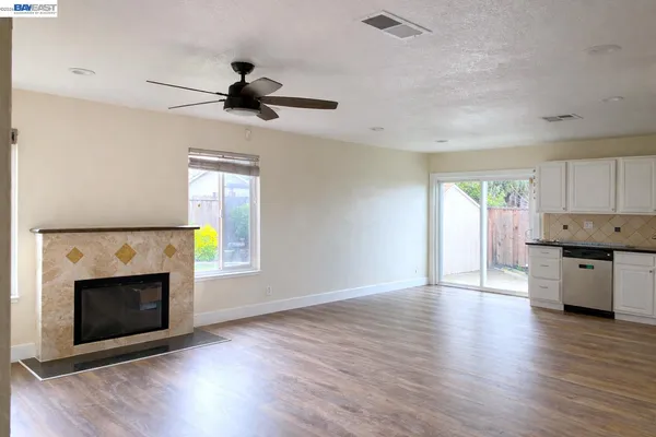 a view of a kitchen and an empty room with a fireplace