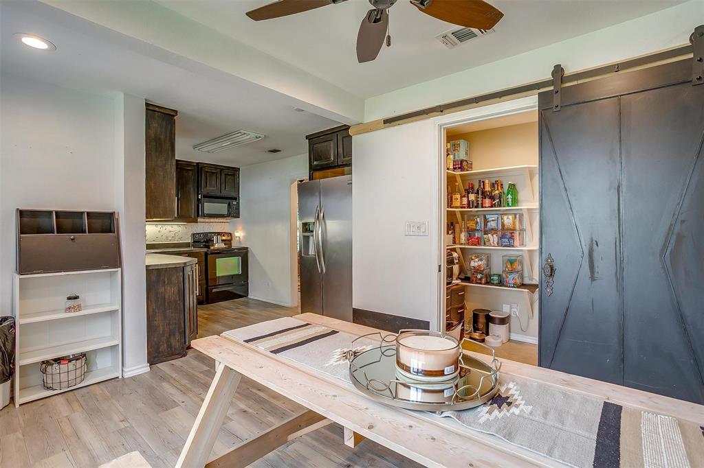 3147 Tin Top Road Weatherford, TX 76087 - Photo 18 of 40 a kitchen with stainless steel appliances kitchen island granite countertop a table chairs in it and wooden floors