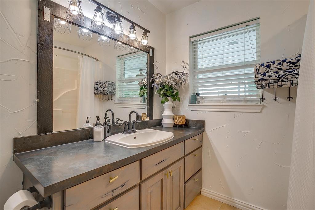 3147 Tin Top Road Weatherford, TX 76087 - Photo 28 of 40 a bathroom with a granite countertop sink a mirror and a window