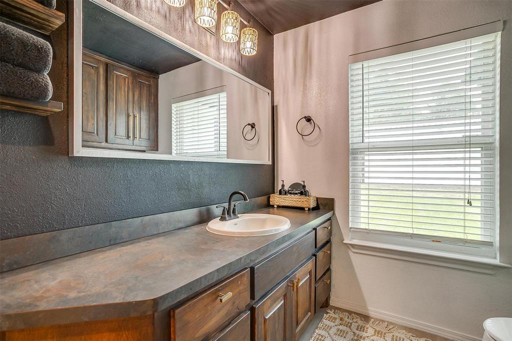 3147 Tin Top Road Weatherford, TX 76087 - Photo 34 of 40 a bathroom with a granite countertop sink a toilet and a window