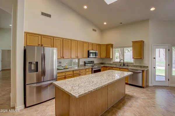 a large kitchen with granite countertop a large counter top stainless steel appliances and cabinets