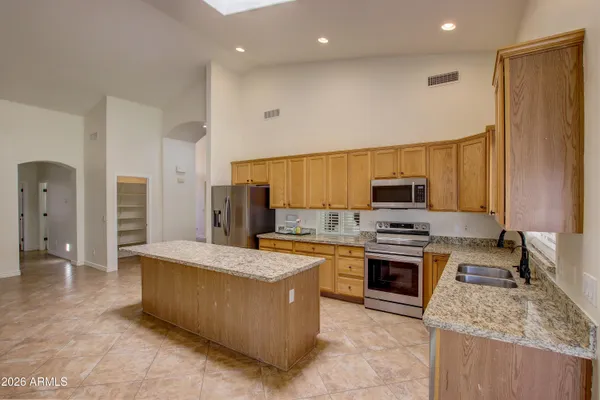 a large kitchen with stainless steel appliances granite countertop a stove a sink and a refrigerator
