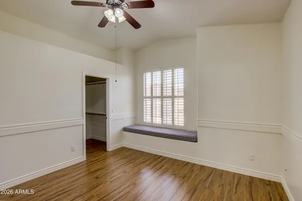 an empty room with wooden floor chandelier and windows