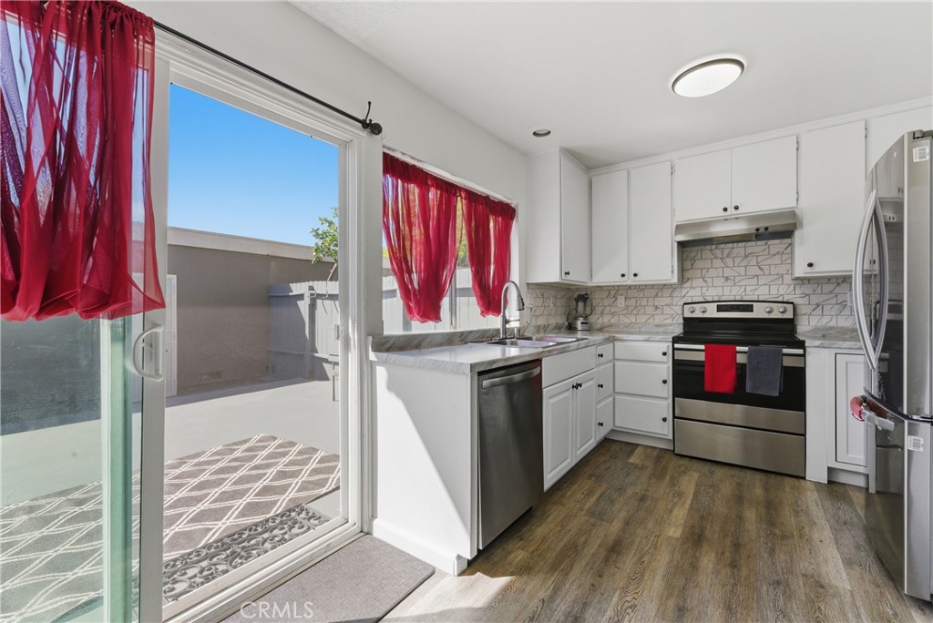 7085 Fulton Way Stanton, CA 90680 - Photo 3 of 34 a kitchen with a refrigerator a stove top oven a sink and dishwasher with wooden floor