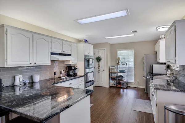 a kitchen with granite countertop a stove a sink a refrigerator and wooden floor
