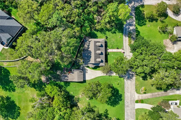 an aerial view of a house with a yard and large trees
