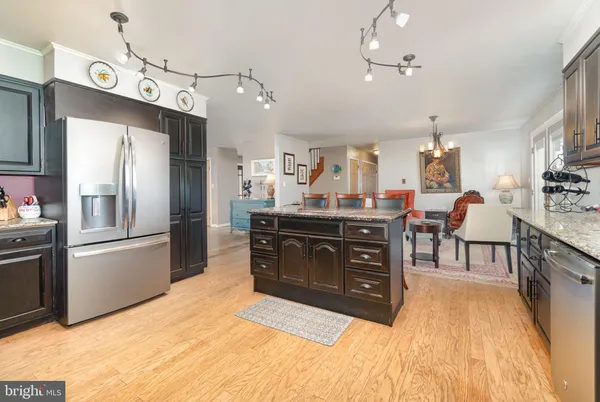 a kitchen with stainless steel appliances kitchen island granite countertop a table chairs sink and cabinets