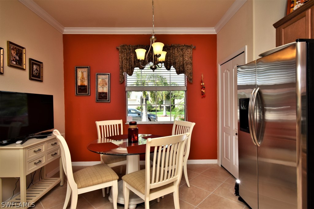 11674 Eros Road Lehigh Acres, FL 33971 - Photo 7 of 35 a dining room with furniture a chandelier a flat screen tv and a refrigerator