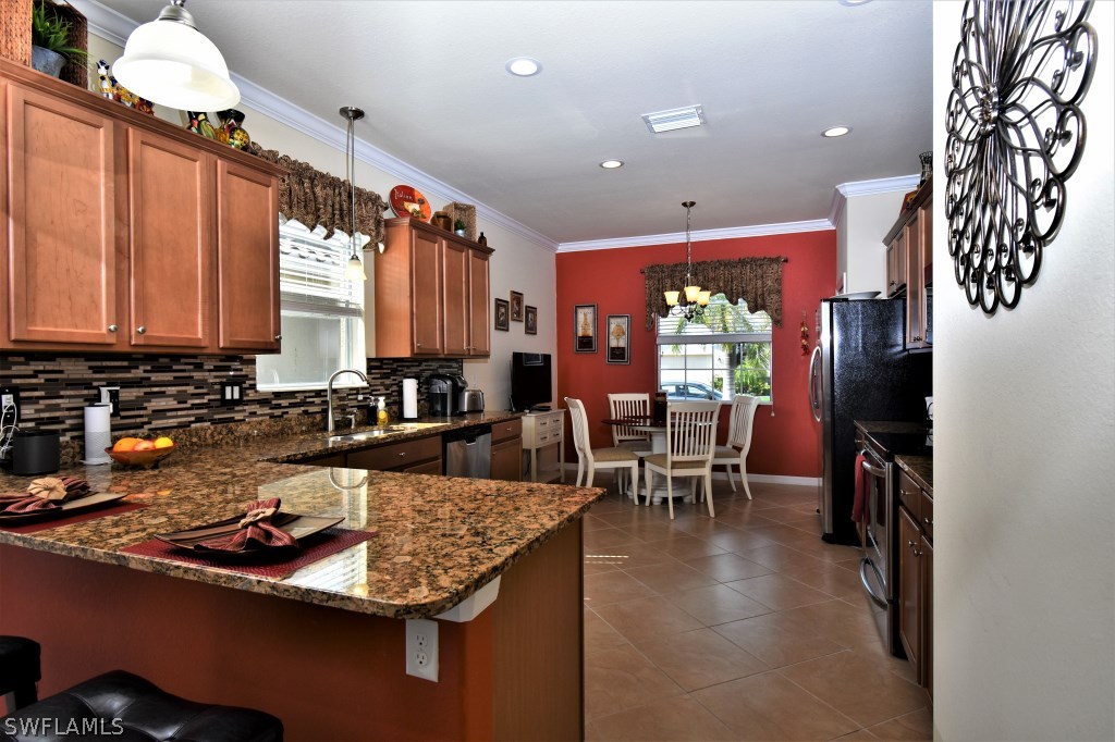 11674 Eros Road Lehigh Acres, FL 33971 - Photo 9 of 35 a kitchen with stainless steel appliances granite countertop a stove refrigerator a dining table and chairs with wooden floor