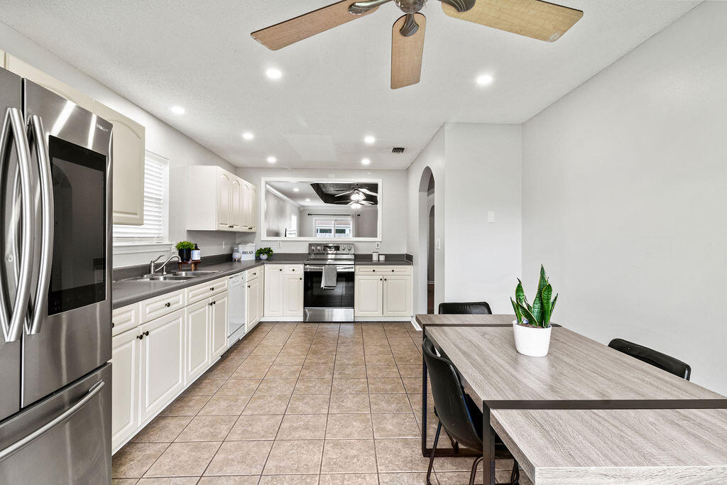 1791 Old Ranch Road Fort Walton Beach, FL 32547 - Photo 6 of 30 a kitchen with stainless steel appliances kitchen island granite countertop a refrigerator a sink dishwasher a stove a dining table and chairs with wooden floor