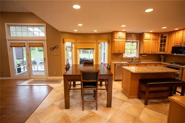 a open kitchen with stainless steel appliances granite countertop a stove a sink a dining table and chairs with wooden floor