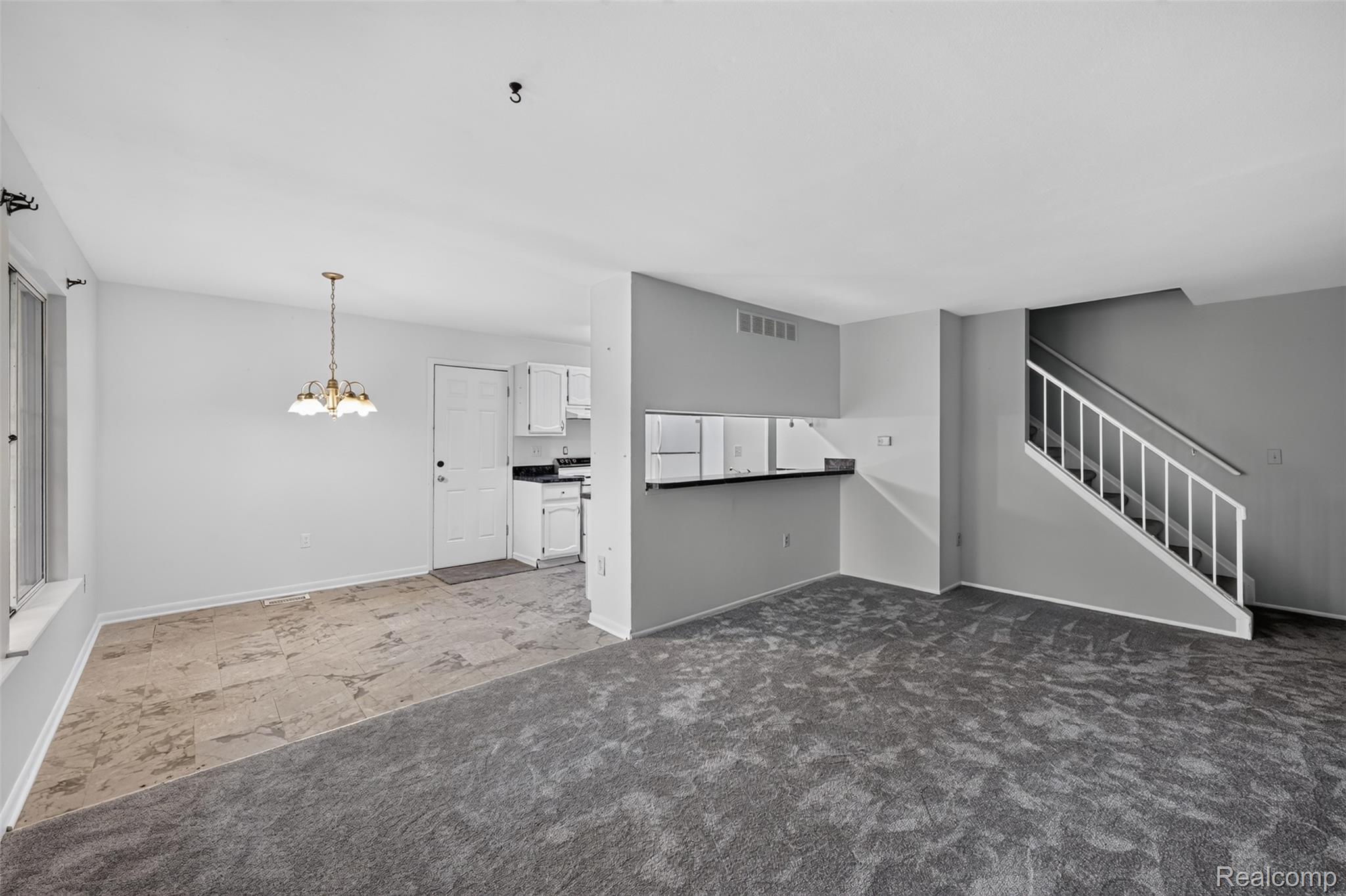 8324 North Genesee Road Mount Morris, MI 48458 - Photo 7 of 33 Open concept living area featuring contrasting flooring, a white-railed staircase, and a kitchen pass-through
