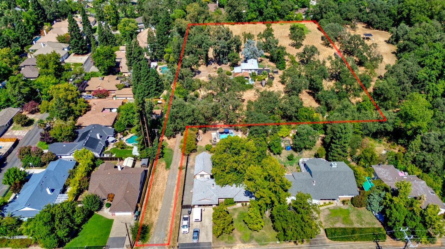 an aerial view of residential house with outdoor space and trees all around