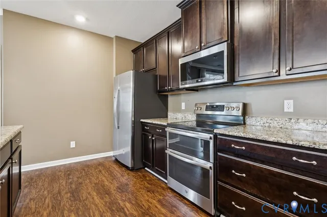 a kitchen with stainless steel appliances granite countertop a refrigerator and a stove top oven