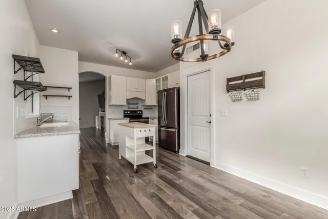 a kitchen with stainless steel appliances a refrigerator a sink dishwasher a stove and white cabinets with wooden floor