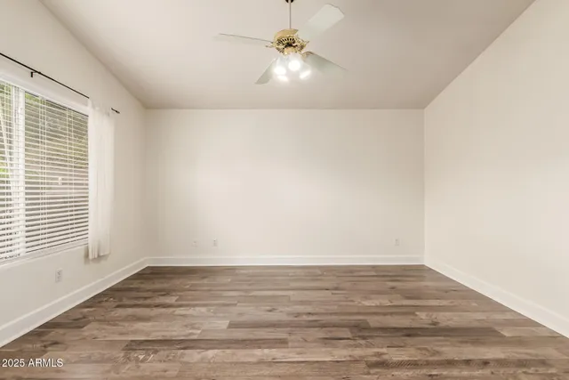 a view of an empty room with window and a ceiling fan