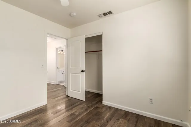 a view of an empty room with wooden floor and closet