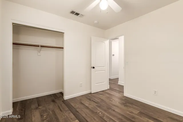 an empty room with wooden floor and a ceiling fan