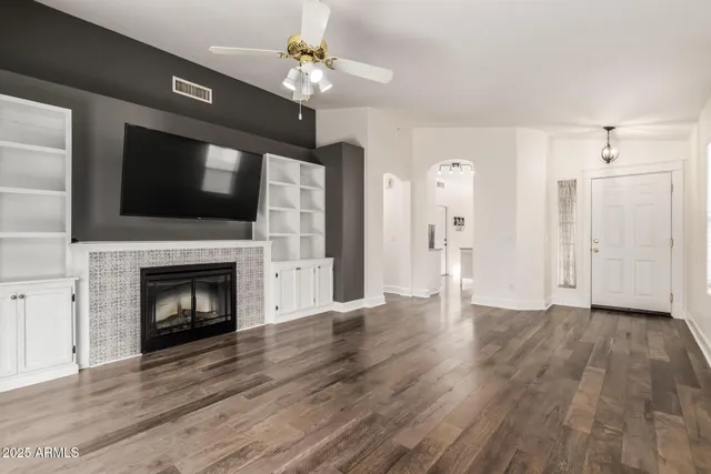 a view of an empty room with wooden floor fireplace and a window